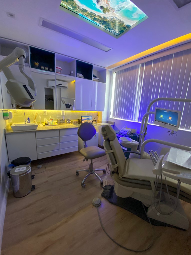 Consultório da Fibro Odontologia com a cadeira e a tela no teto mostrando uma praia